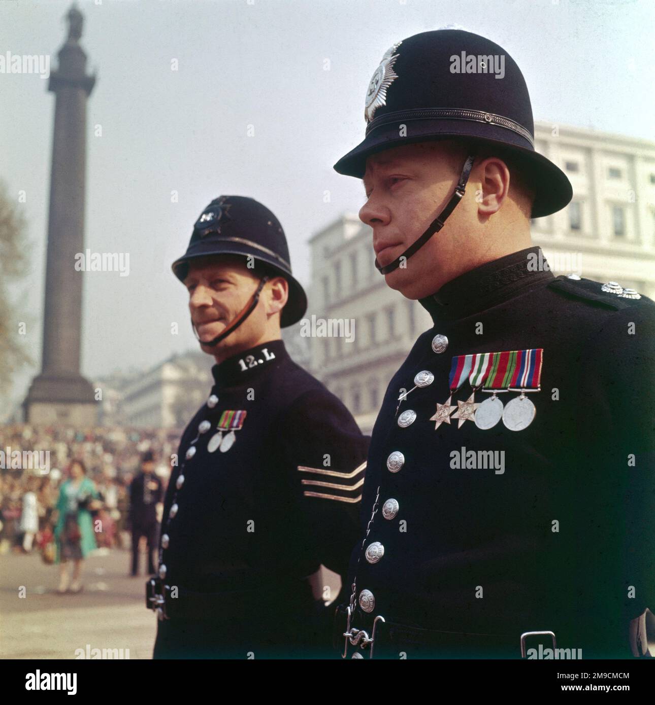 Zwei Polizisten, beide mit Medaillen geschmückt, stehen zusammen im Dienst am Trafalgar Square, London, England. Stockfoto