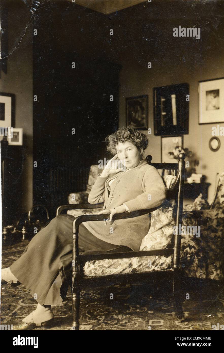 Eine Frau sitzt zu Hause auf ihrem Stuhl Stockfoto