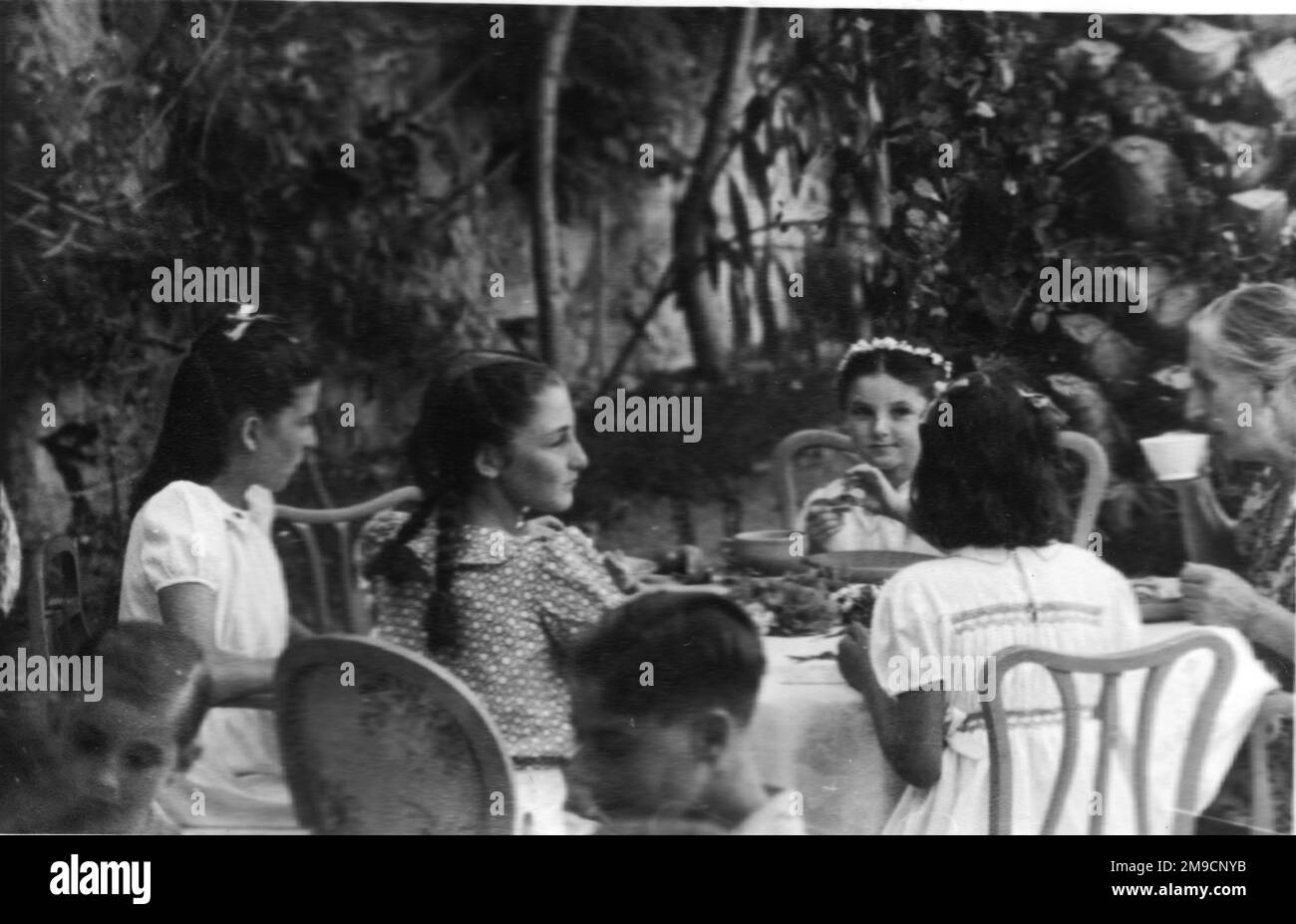 Vier junge italienische Mädchen sitzen mit einer älteren Frau an einem Tisch. Stockfoto