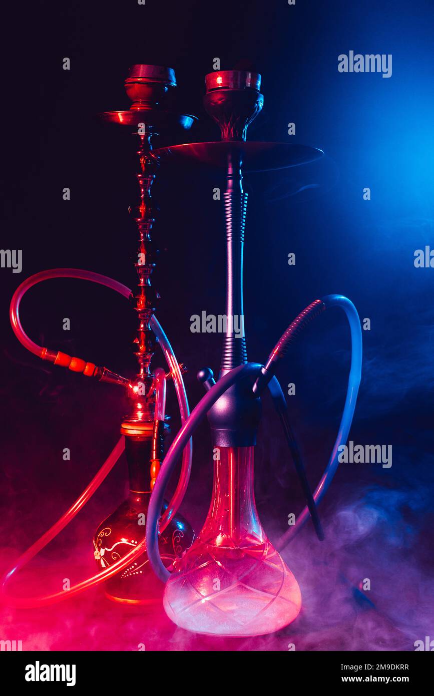 Moderne Hookah, Shisha auf rauchschwarzem Hintergrund mit Neonbeleuchtung Stockfoto