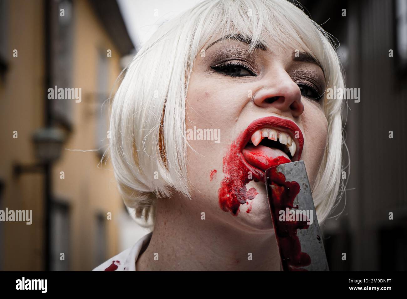 Porträt eines blutigen Vampirs, der an einem blutigen Messer leckt Stockfoto