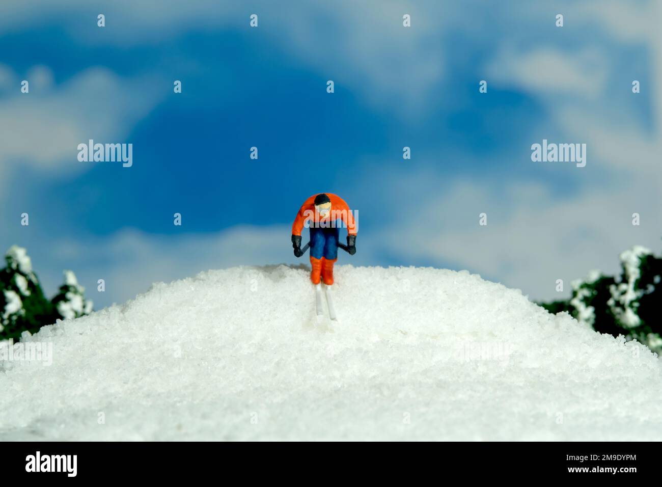 Miniatur-Menschen-Spielzeug-Figuren-Fotografie. Wintersport. Ein männlicher Abfahrtsski-Rennfahrer rutscht vom Gipfel des Hügels herunter. Bildfoto Stockfoto