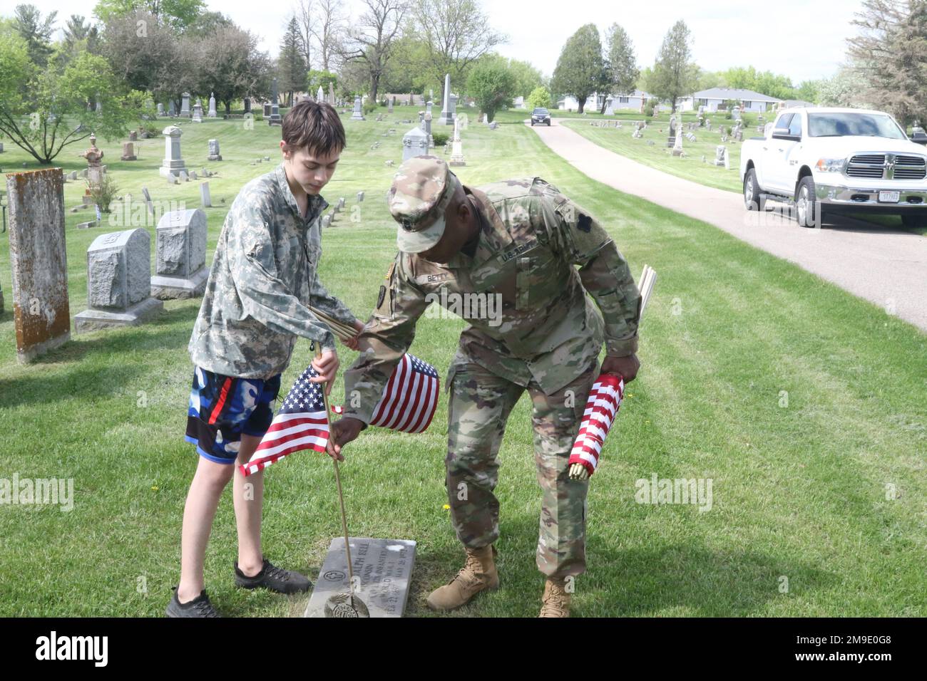 USA Major Gregory Betty, Kommandoleiter der 88. Bereitschaftsabteilung, Major und Isiah Hyma platzieren eine amerikanische Flagge auf dem Woodlawn Friedhof am Grab eines amerikanischen Veteranen. Der Friedhof war der letzte Halt des Ruck für den 5 km langen sturzmarsch in Sparta Wisconsin, 18. Mai 2022. Stockfoto