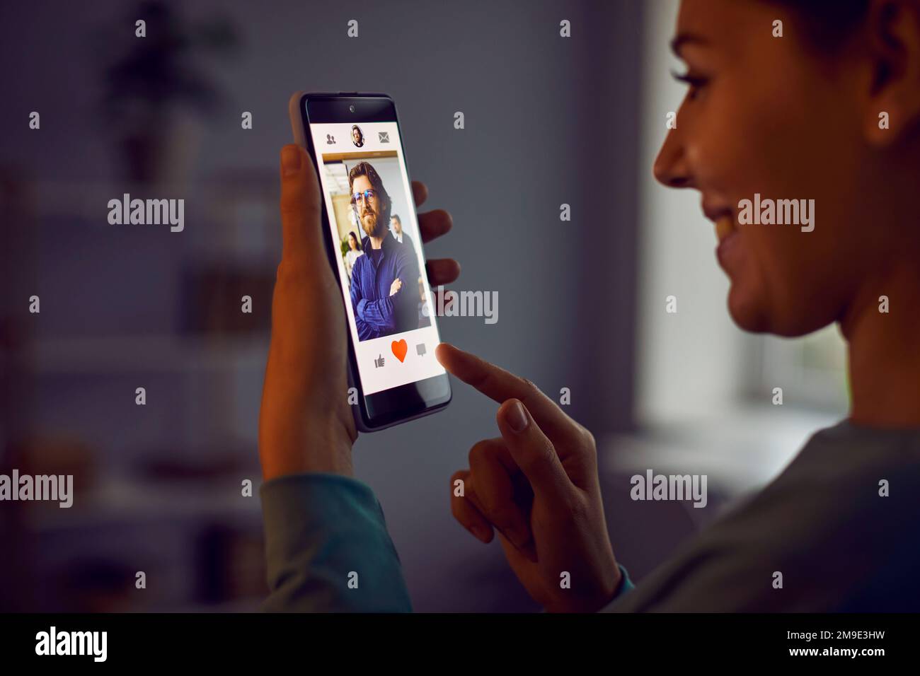 Fröhliche Frau drückt roten Herzknopf im Profil eines Mannes, den sie in der Dating-App mag. Stockfoto