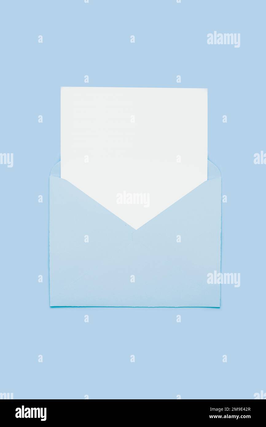 Nahaufnahme auf leerer weißer Papierkarte in blauem, geöffnetem Umschlag isoliert auf blauem pastellfarbenem Hintergrund. Liebesbrief-Minimalkonzept. Konzeptionelle Layoutvorlage mit Textposition auf Postkarte. Modell Stockfoto