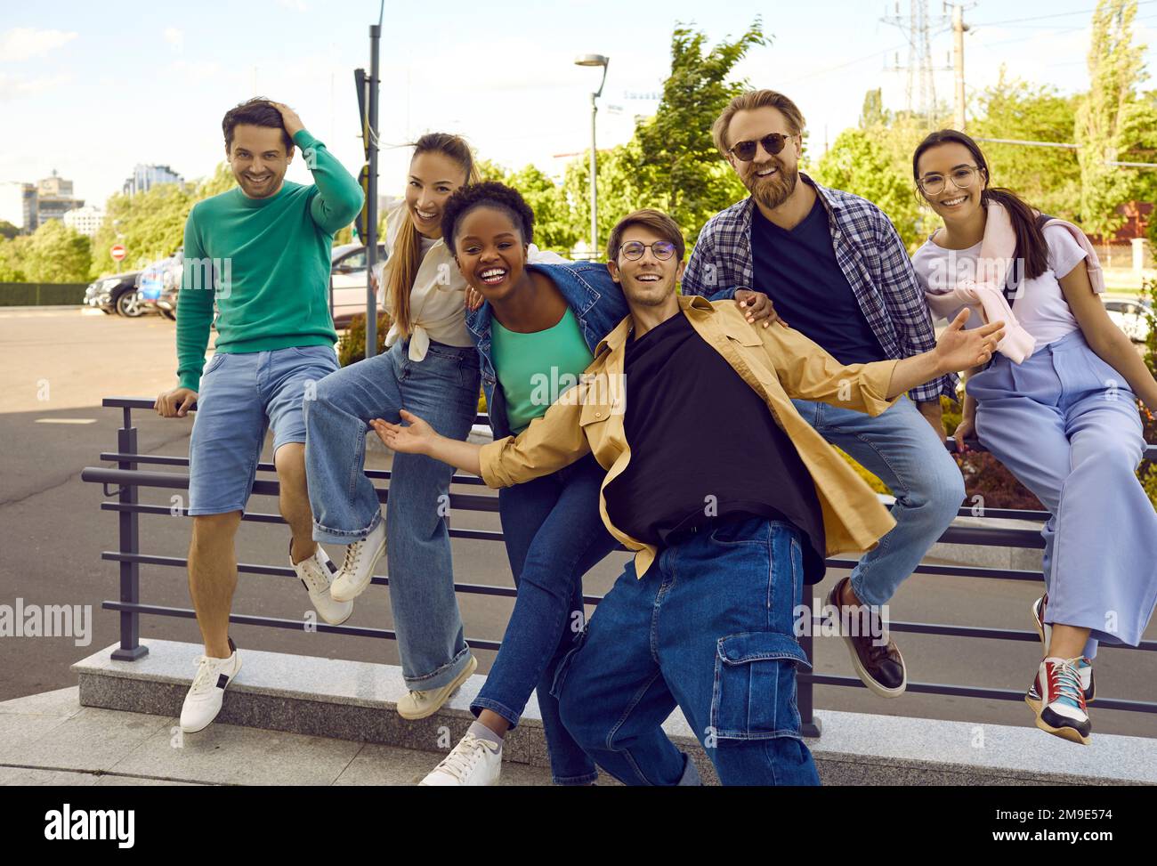 Fröhliche männliche und weibliche Freunde haben Spaß und lachen zusammen auf den Straßen der Stadt im Sommer. Stockfoto