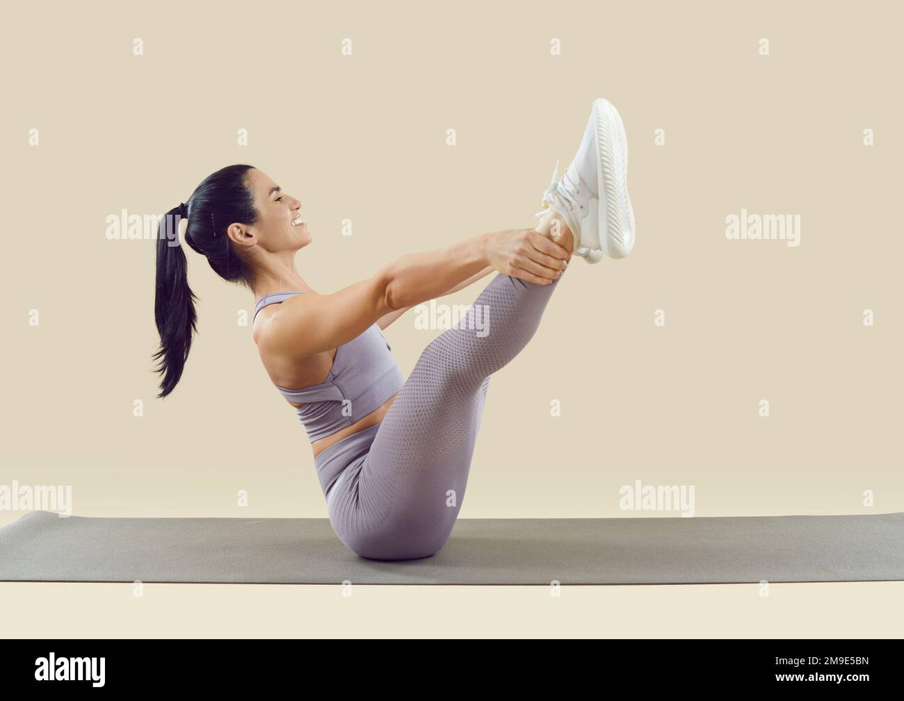 Seitenansicht einer Frau, die Sport macht und auf einer Yogamatte körperliche Übungen macht Stockfoto