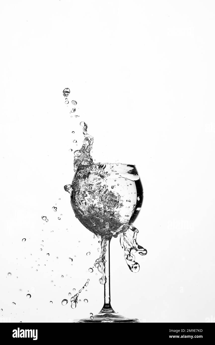 Hintergrundbeleuchtung, Wasserfontäne, Tropfen in Glas, weißer Hintergrund Stockfoto