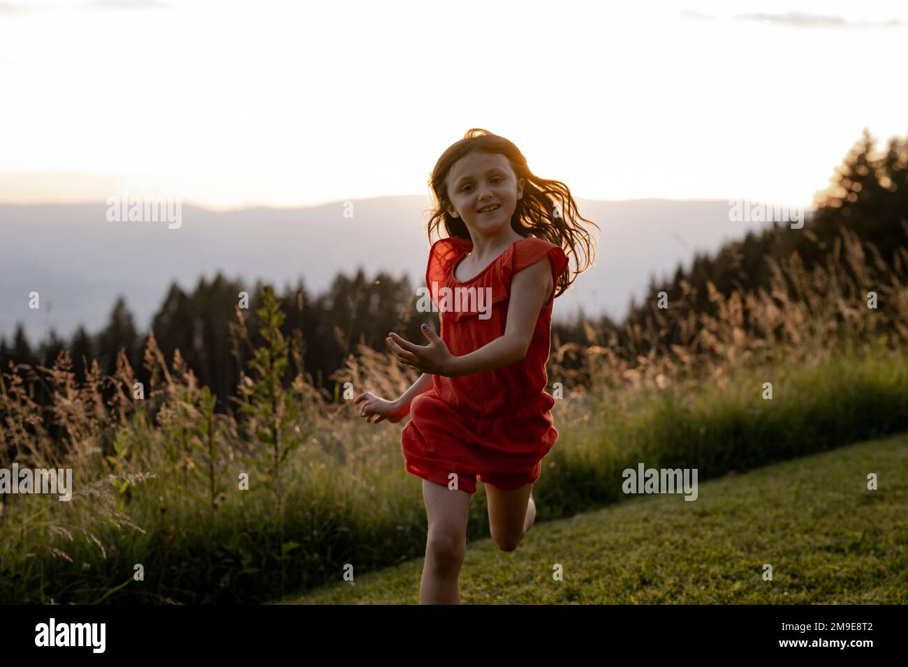 Mädchen, 8 Jahre, läuft auf einer Wiese bei Sonnenuntergang, Kärnten, Österreich Stockfoto