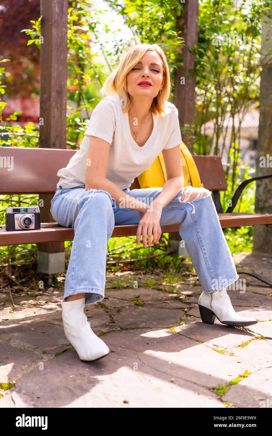 Blonde Touristin im Sommerurlaub, die auf einer Bank im Park sitzt Stockfoto