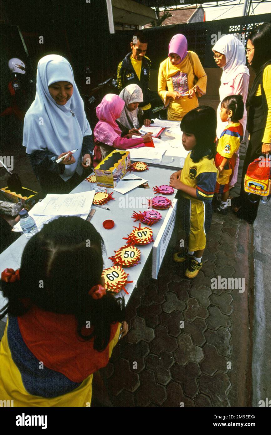 Frauen bereiten einen Malwettbewerb für Kinder in der Gegend von Gegerkalong vor, dem Zentrum der Aktivitäten von Daarut Tauhiid, einer islamischen Institution, die von dem berühmten indonesischen islamischen Prediger KH Abdullah Gymnastiar mit Sitz in Bandung, West-Java, Indonesien, gegründet wurde. Gymnastiar (allgemein bekannt als AA Gym), Daarut Tauhiid und ihre Geschäftsleitung Manajemen Qolbu (MQ) haben es geschafft, den religiösen Tourismus und die wirtschaftlichen Aktivitäten im Gebiet Gegerkalong in Bandung zu eskalieren. Stockfoto