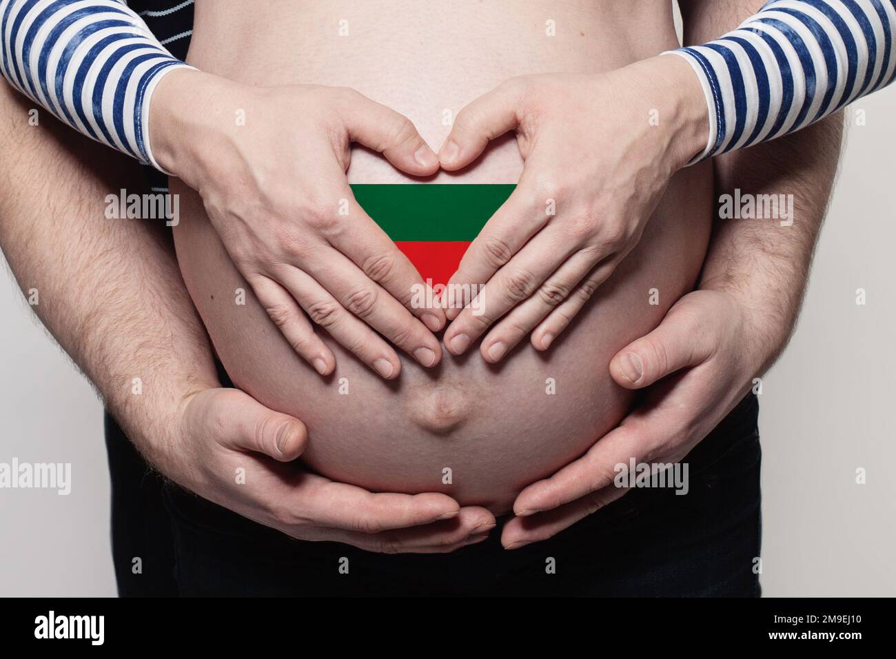 Bulgarisches Familienkonzept. Ein Mann umarmt den Bauch und das Herz einer schwangeren Frau mit der Flagge Bulgariens Stockfoto