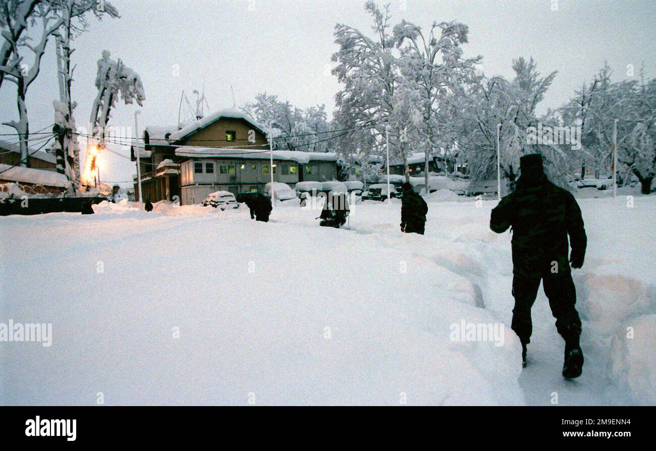 Gerade auf der Rückansicht, mittellange Aufnahme, während multinationale Militärangehörige sich durch 3 Meter Schnee bewegen, während sie in Ilidza, Compound, Sarajevo, Bosnien stationiert sind, um die Operation Joint Forge zu unterstützen. Sarajevo hat in diesem Winter die tiefste Schneemenge seit 50 Jahren entdeckt. Die Straßen waren gesperrt und einige Unternehmen (Straßen und Unternehmen nicht gezeigt) wurden für die vier Tage des intensiven Schneefalls geschlossen. Betrifft Operation/Serie: JOINT FORGE Base: Llidza Land: Bosnien und Herzegowina (BIH) Stockfoto