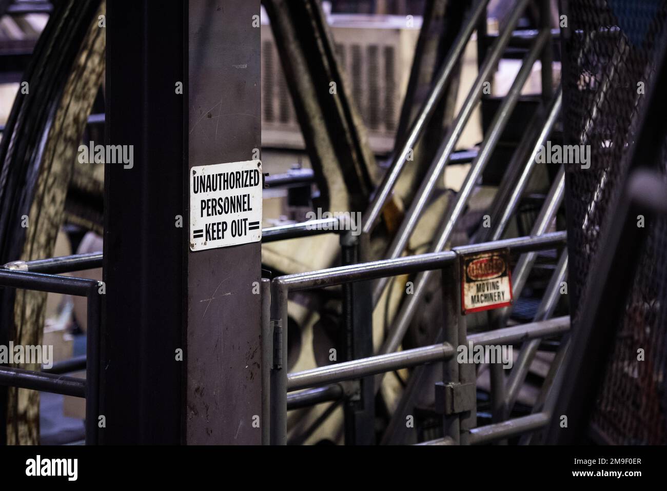 Eine Szene im Inneren eines Industriegebäudes mit einem Warnschild auf einer Metallsäule in der Nähe der gefährlichen Maschine Stockfoto