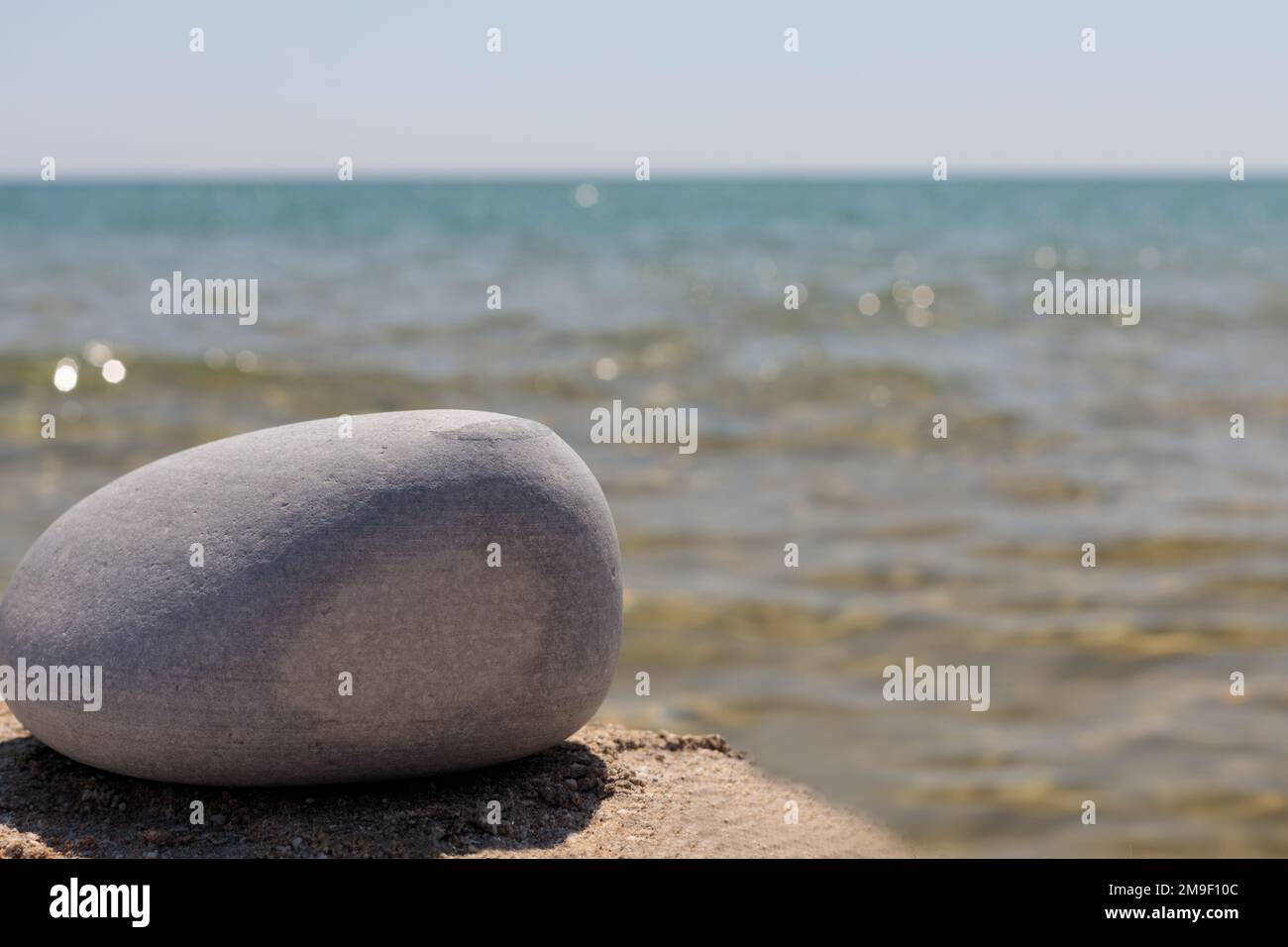 Eine leere Produktvorlage auf einem steinernen, felsigen Sockel vor einem Meereshintergrund, die eine sommerliche Atmosphäre für Modell- oder Werbezwecke schafft. Stockfoto