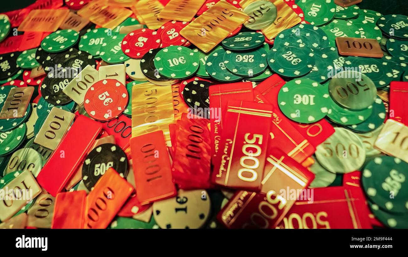 Glücksspiel-Poker-Chips, die zufällig über einen grünen Pokertisch verteilt sind. Die chaotische Anordnung der Chips deutet auf eine Abhängigkeit vom Nervenkitzel hin Stockfoto