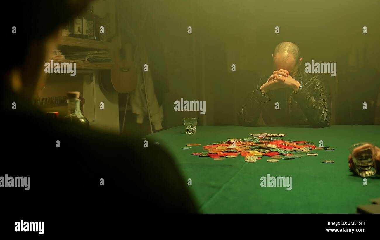 Ein aufgeregter Pokerspieler gewinnt das Spiel, zeigt seine Karten und nimmt alle auf dem Tisch verteilten Pokerchips. Gewinnen im Glücksspiel. Stockfoto