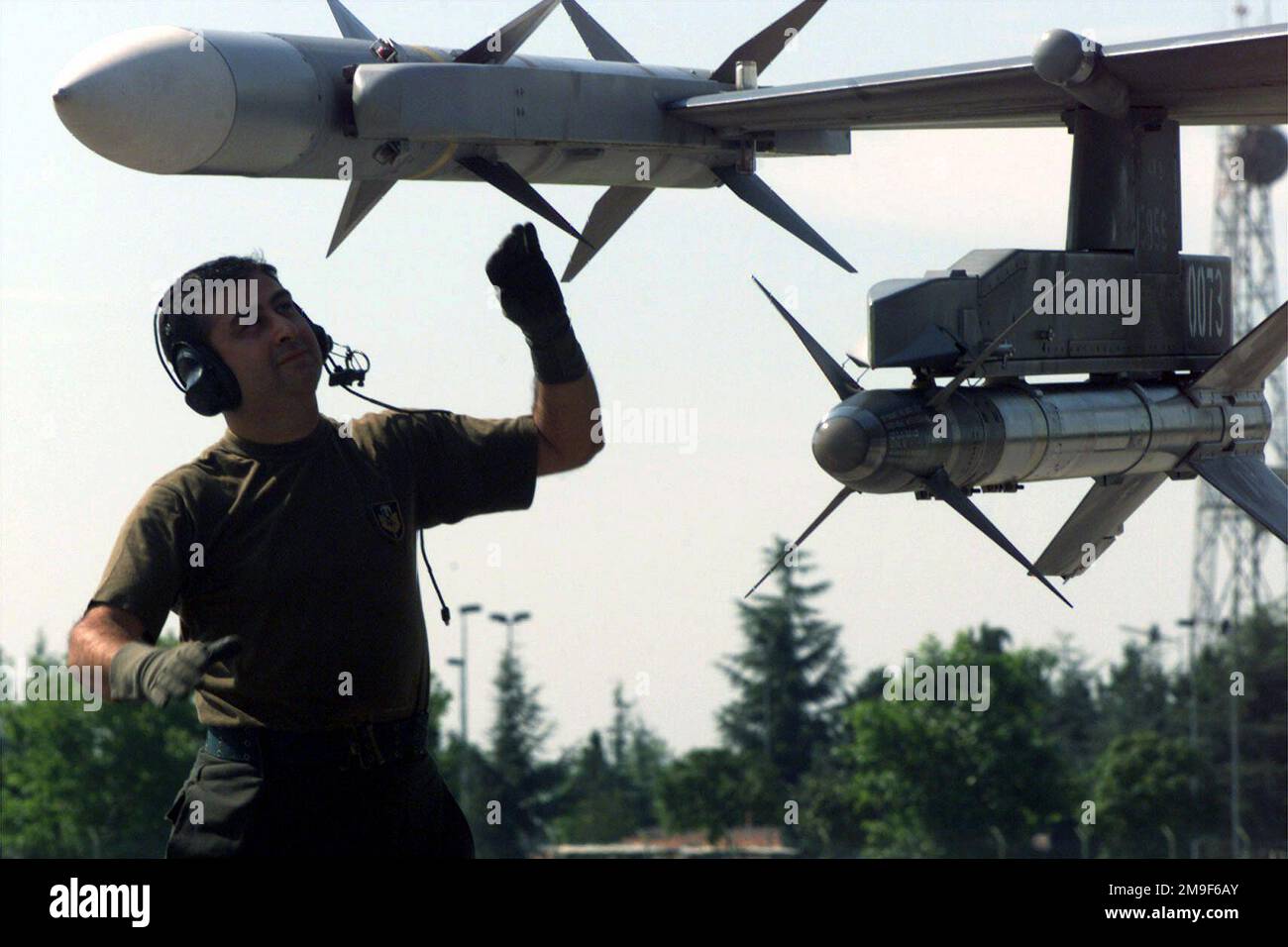 Direkt auf mittlerer Schusslinie, während türkischer Luftwaffenoffizier Mustafa Sen, T-22 Wartungsgruppe die Waffensysteme der türkischen F-16C vor dem Start überprüft. Sergeant Sen wird nach Aviano entsandt, um die Operation Joint Forge der Nordatlantikvertrags-Organisation zu unterstützen. Unter dem rechten Flügel des Luftfahrzeugs ist eine LUFT-Luft-Sidewinder-Rakete AIM-9 und am Ende des rechten Flügels eine Luft-Luft-Rakete AIM-120 AMRAAM angebracht. Direkt auf mittlerer Schusslinie, während türkischer Luftwaffenoffizier Mustafa Sen, T-22 Wartungsgruppe die Waffensysteme der türkischen F-16C vor dem Start überprüft. Sergeant Sen ist in stationiert Stockfoto