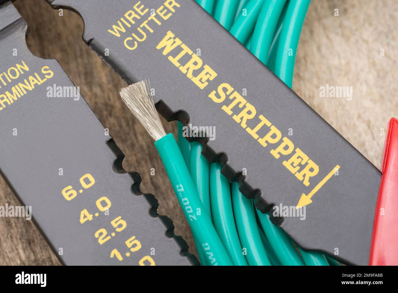 Nahaufnahme des in China hergestellten Abisolierers und Drahtschneiders ohne Markenkennzeichnung für 26-10AWG-Draht (siehe Hinweise) mit der Rolle eines grünen, silikonummantelten Drahts. Stockfoto