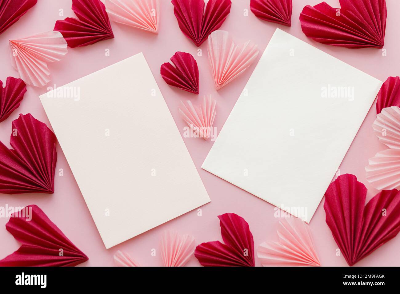 Leere zwei Karten und schicke rote und pinke Herzen liegen flach auf pinkfarbenem Papier. Kreative, moderne Grußkarten mit Platz für Text. Fröhliche Va Stockfoto