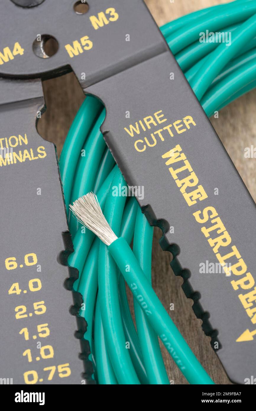 Nahaufnahme des in China hergestellten Abisolierers und Drahtschneiders ohne Markenkennzeichnung für 26-10AWG-Draht (siehe Hinweise) mit der Rolle eines grünen, silikonummantelten Drahts. Stockfoto