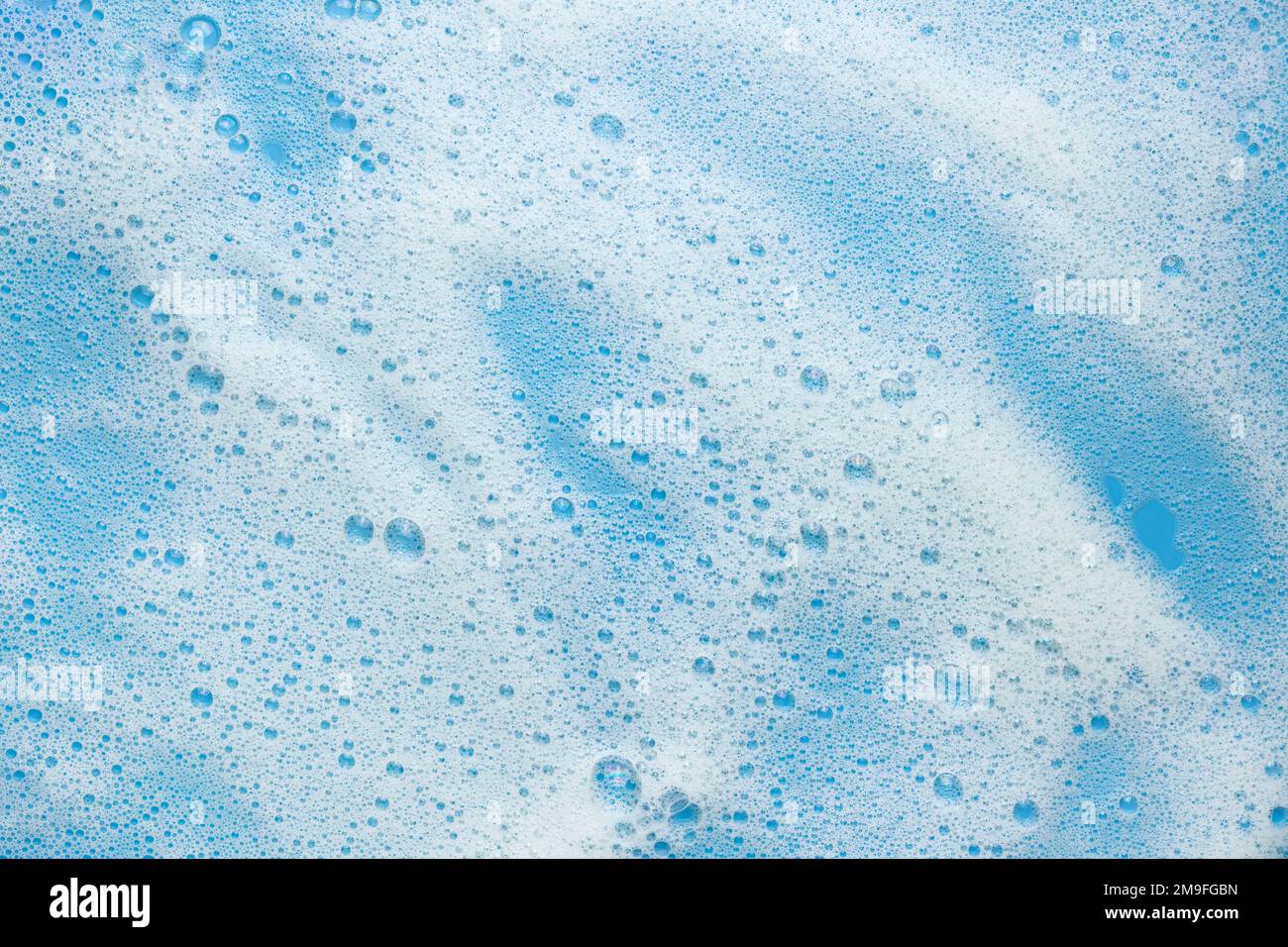 Weißer Schaumschaum auf blauem Hintergrund. Konzept für Schaumprodukte, Kosmetika oder Reinigungsmittel. Stockfoto