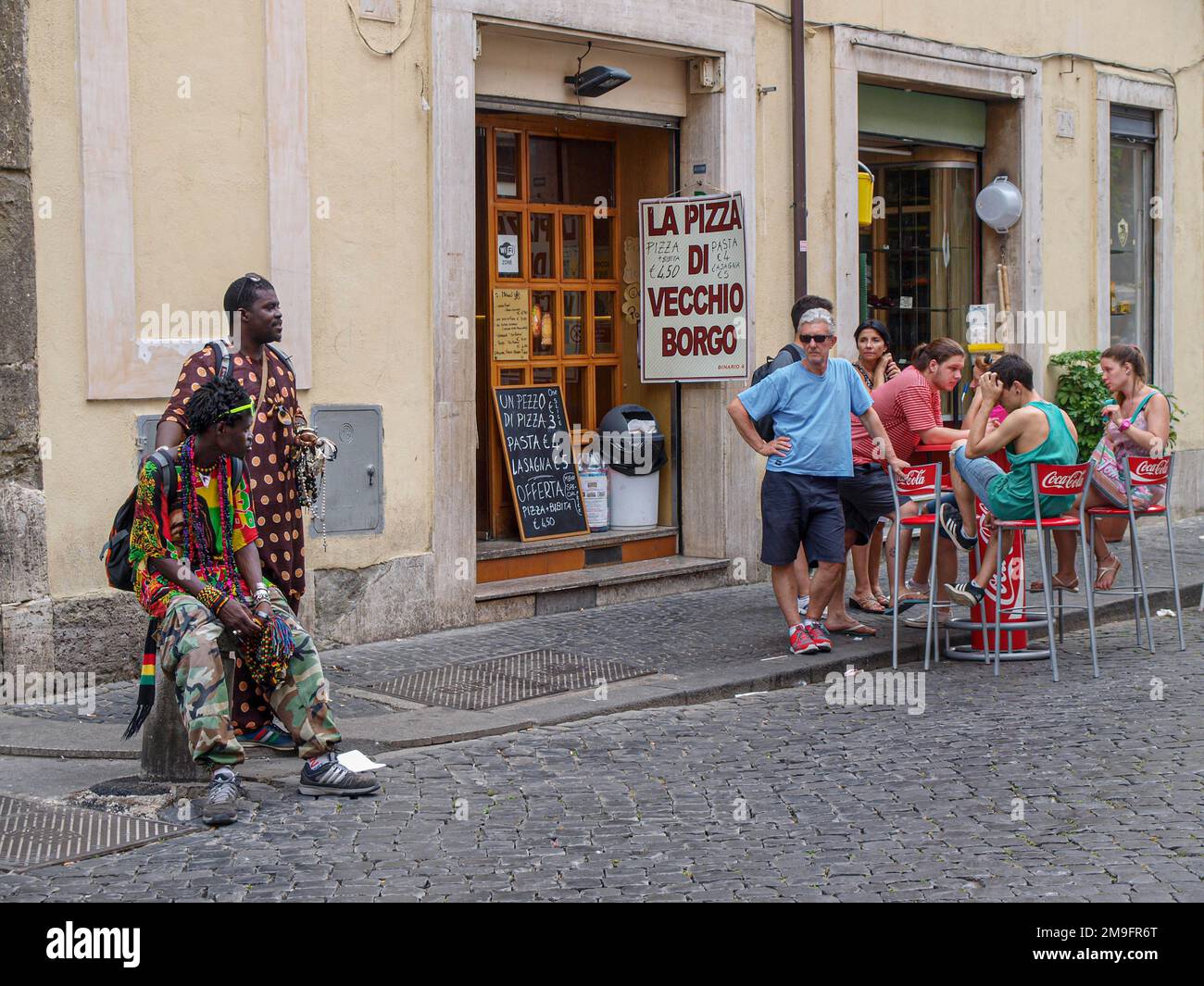 Migranten sitzen getrennt neben den Einheimischen an der Straße in Rom Stockfoto