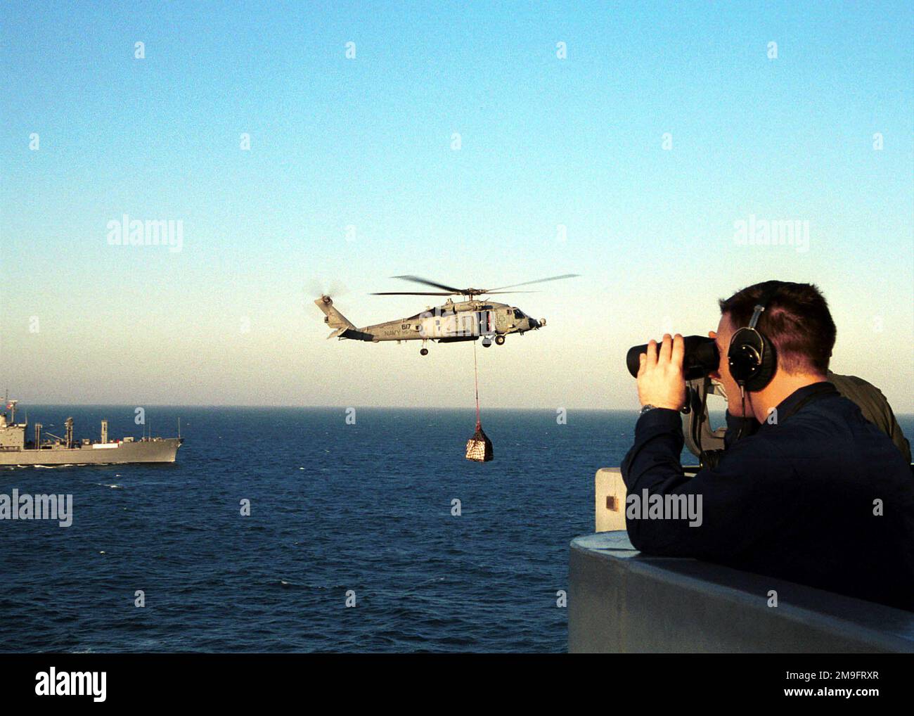 Ein US Navy Boatswain's Mate verwendet Ferngläser, um ein Auge auf einen SH-53F Hubschrauber von Anti-U-Boot-Geschwader Sieben (HS-7) zu werfen, während er Ladengeschäfte von USNS KANAWHA (T-AO 96) zum Flugdeck der USS HARRY S. TRUMAN (CVN 75) während einer vertikalen Wiederauffüllung auf See befördert. Truman ist auf Station im Persischen Golf, um die Operation SÜDWACHE zu unterstützen. Betreff Betrieb/Serie: SÜDLICHE WACHSTATION: USS Harry S. Truman (CVN 75) Stockfoto