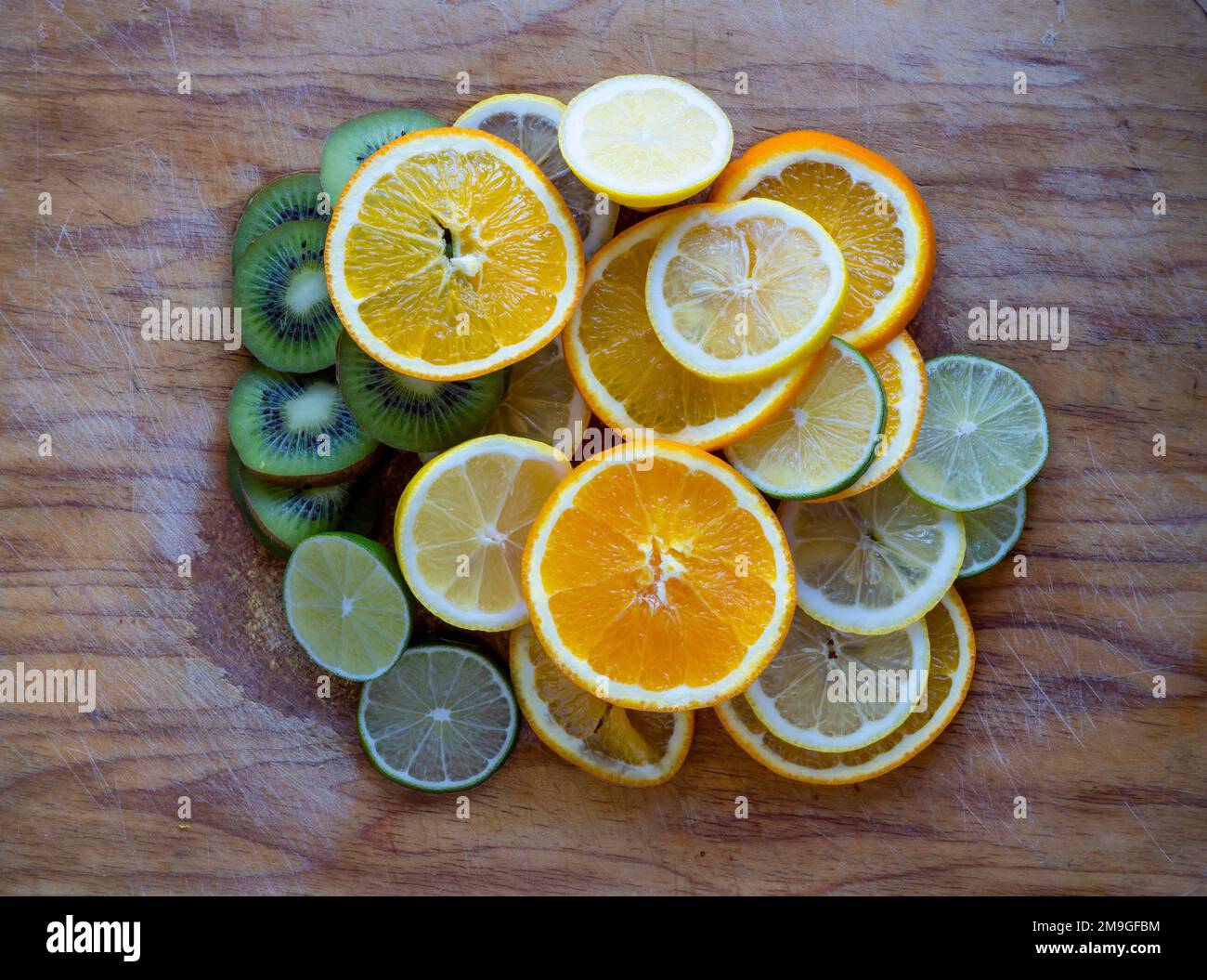 Geschnittene Orangen-, Zitronen- und Kiwis-Früchte, die sich auf einem Holzbrett stapeln Stockfoto