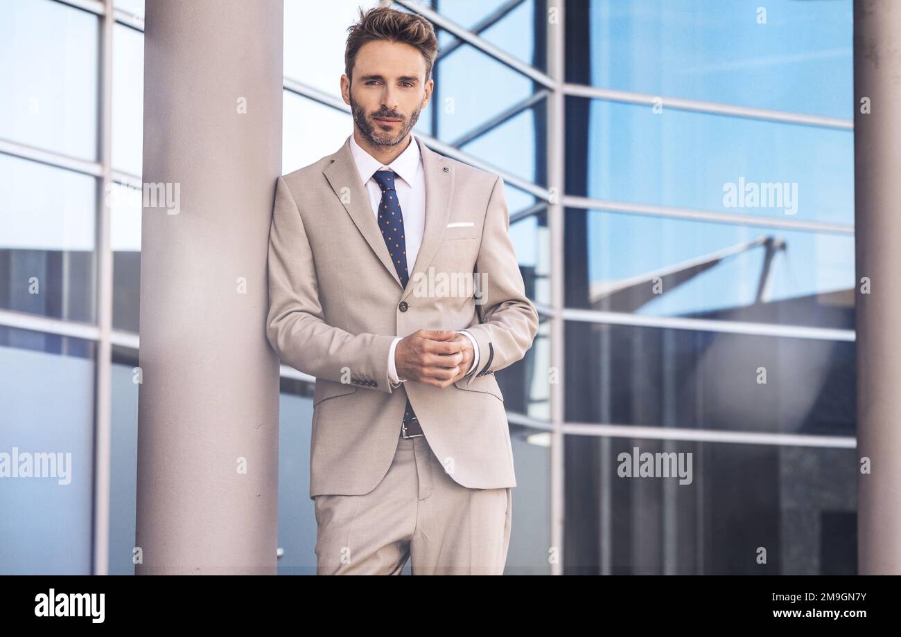 Ein hübsches Männermodell, das am Bürogebäude steht und einen silbernen Anzug trägt Stockfoto