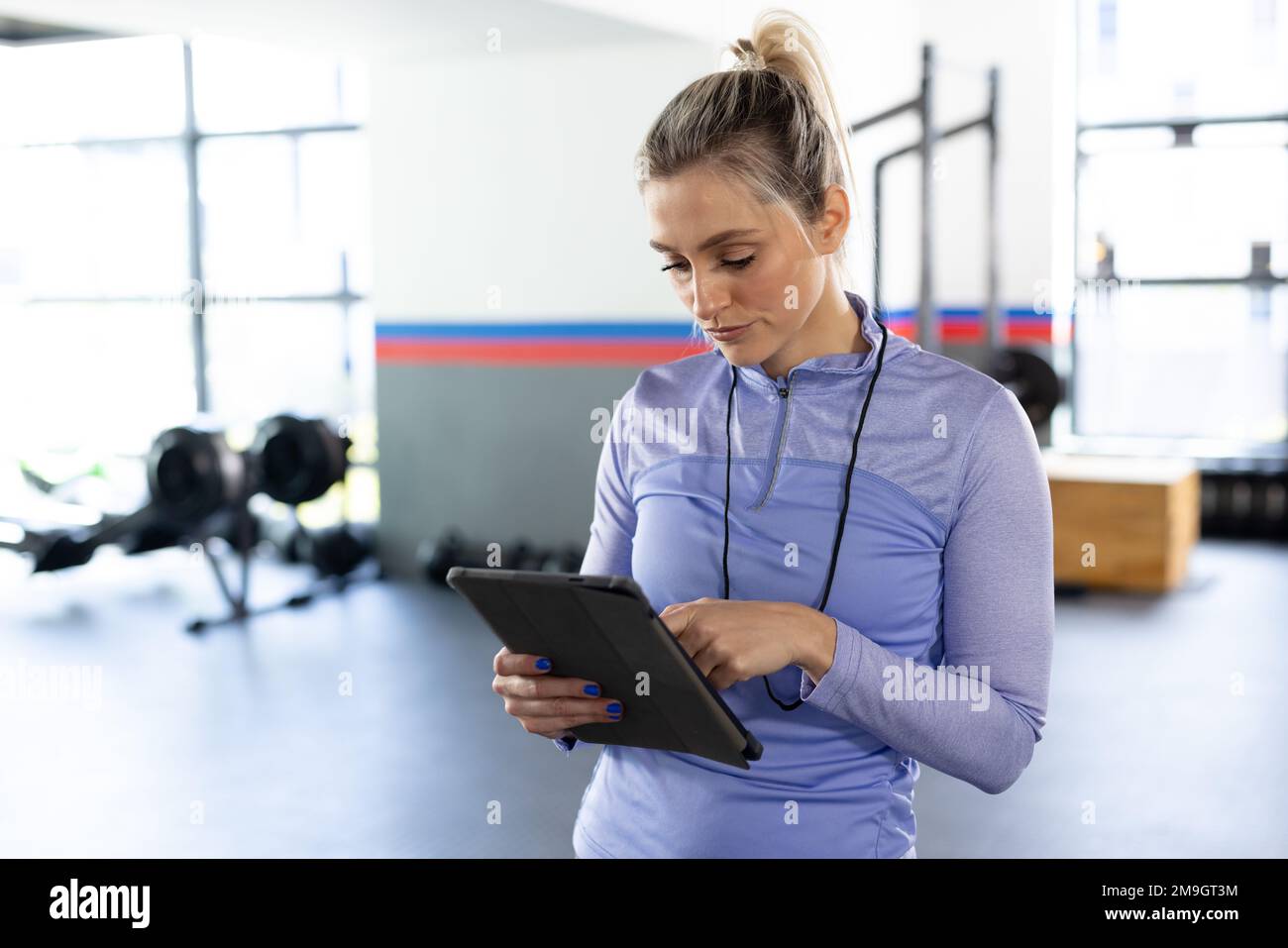 Kaukasische fitte Frau im Stehen mit Tablet im Fitnessstudio Stockfoto