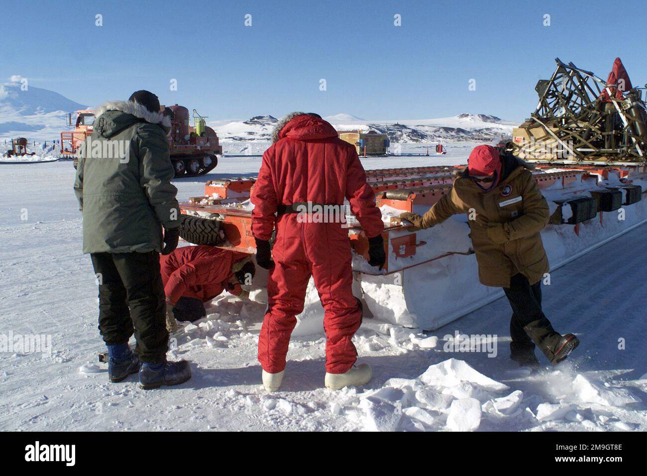 Zivile Frachtarbeiter entfernen Schneefälle, die von einem Frachtschlitten fallen, während er von der Rampe eines C-141C-Starlifters weggezogen wird. Es parkt auf dem Ross-Eisregal in der Nähe der McMurdo-Station in der Antarktis, während der Operation DEEP FREEZE 2001. Betreff Operation/Serie: TIEFKÜHL 2001 Basis: McMurdo Station Country: Antarktis (ATA) Stockfoto
