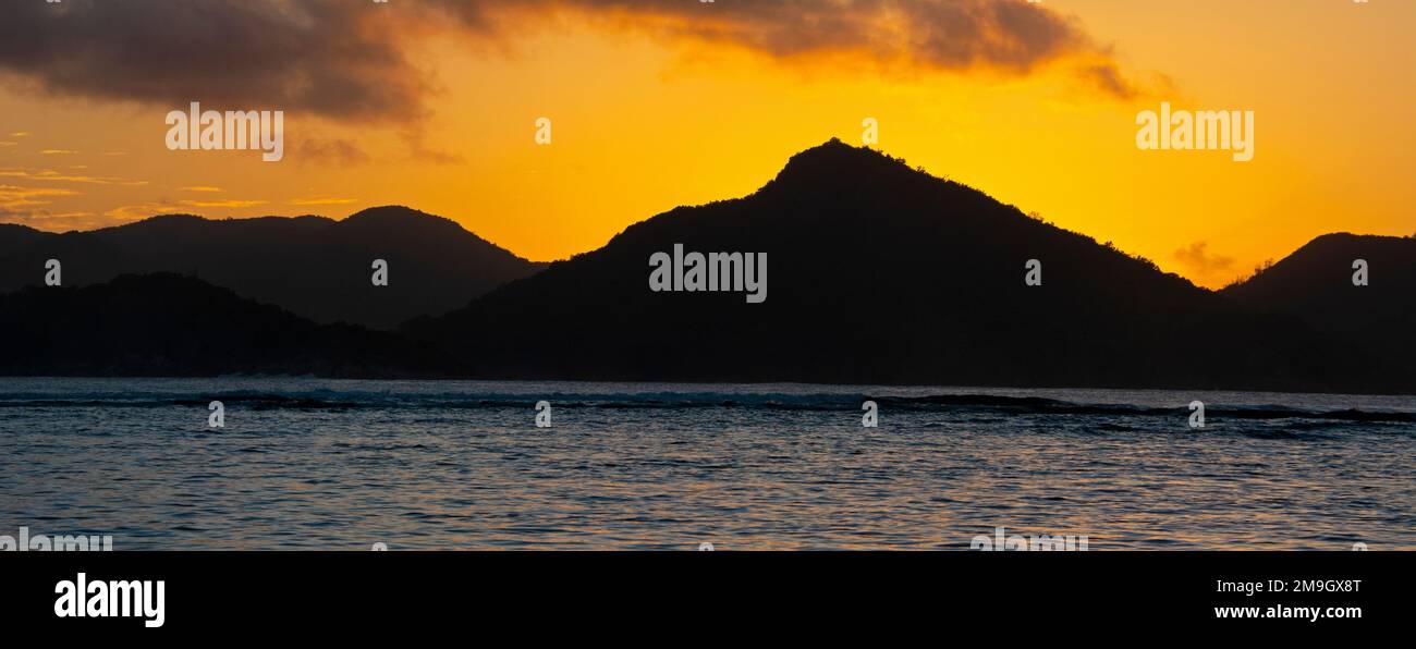 Blick auf die Meereslandschaft mit silhouettierten Hügeln bei Sonnenuntergang, La Digue, Seychellen Stockfoto