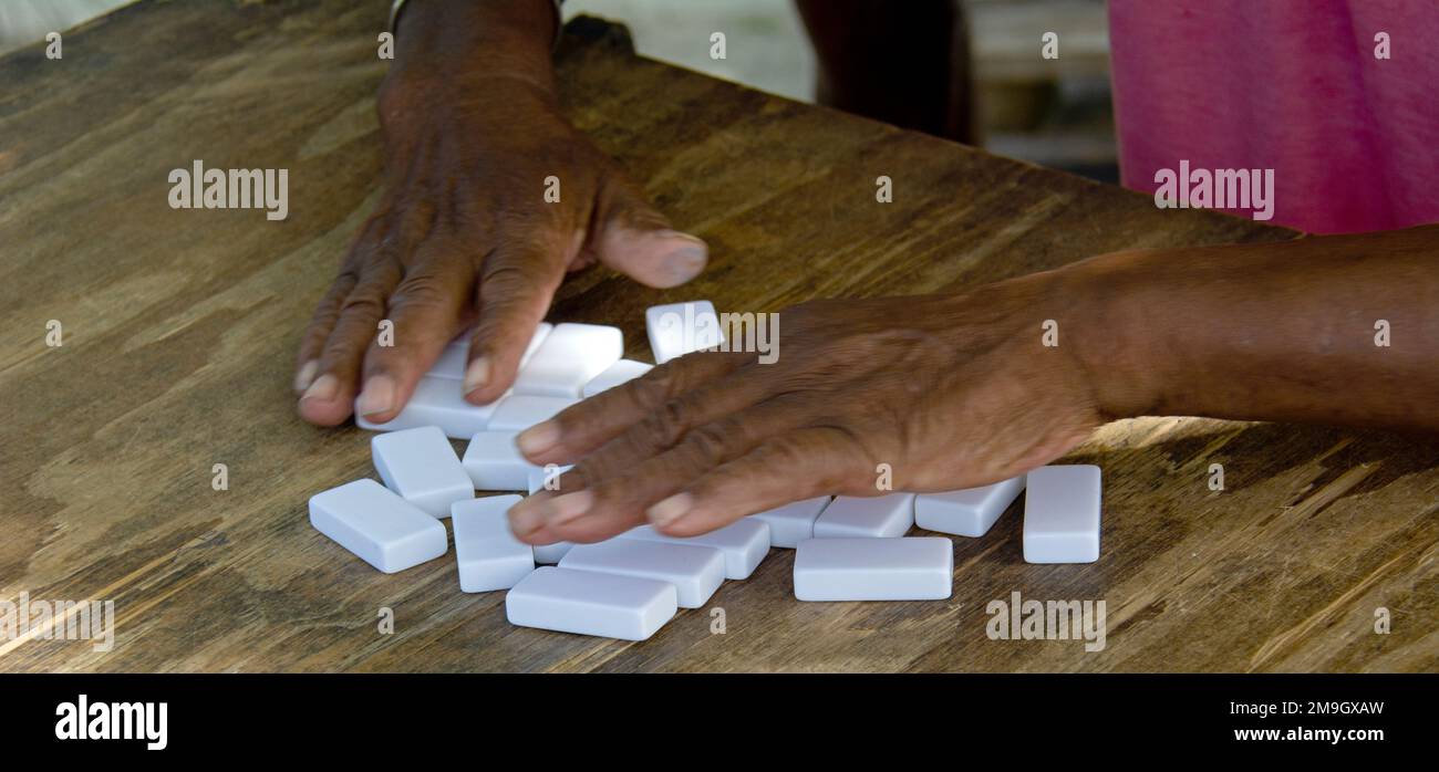 Hände von Männern, die Dominospiele spielen, auf Holztischen, La Passe, La Digue, Seychellen Stockfoto