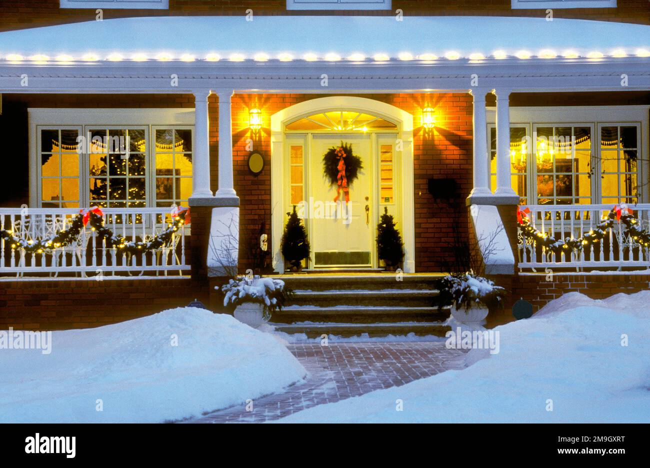 Eingangstür und Veranda des Hauses mit Weihnachtsdekorationen am Abend Stockfoto