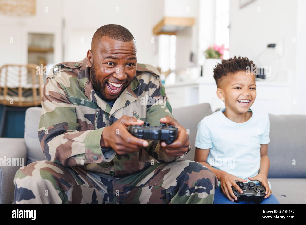 Glücklicher afroamerikanischer Vater in Militäruniform und sein Sohn spielt Videospiele Stockfoto