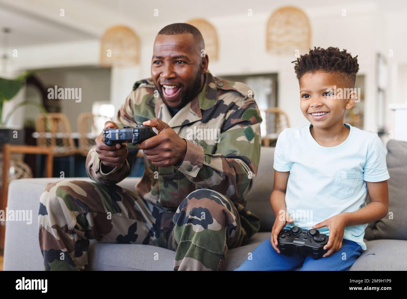 Glücklicher afroamerikanischer Vater in Militäruniform und sein Sohn spielt Videospiele Stockfoto