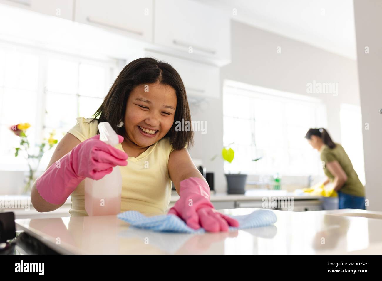 Glückliche asiatische Mutter und Tochter putzen zusammen die Küche Stockfoto