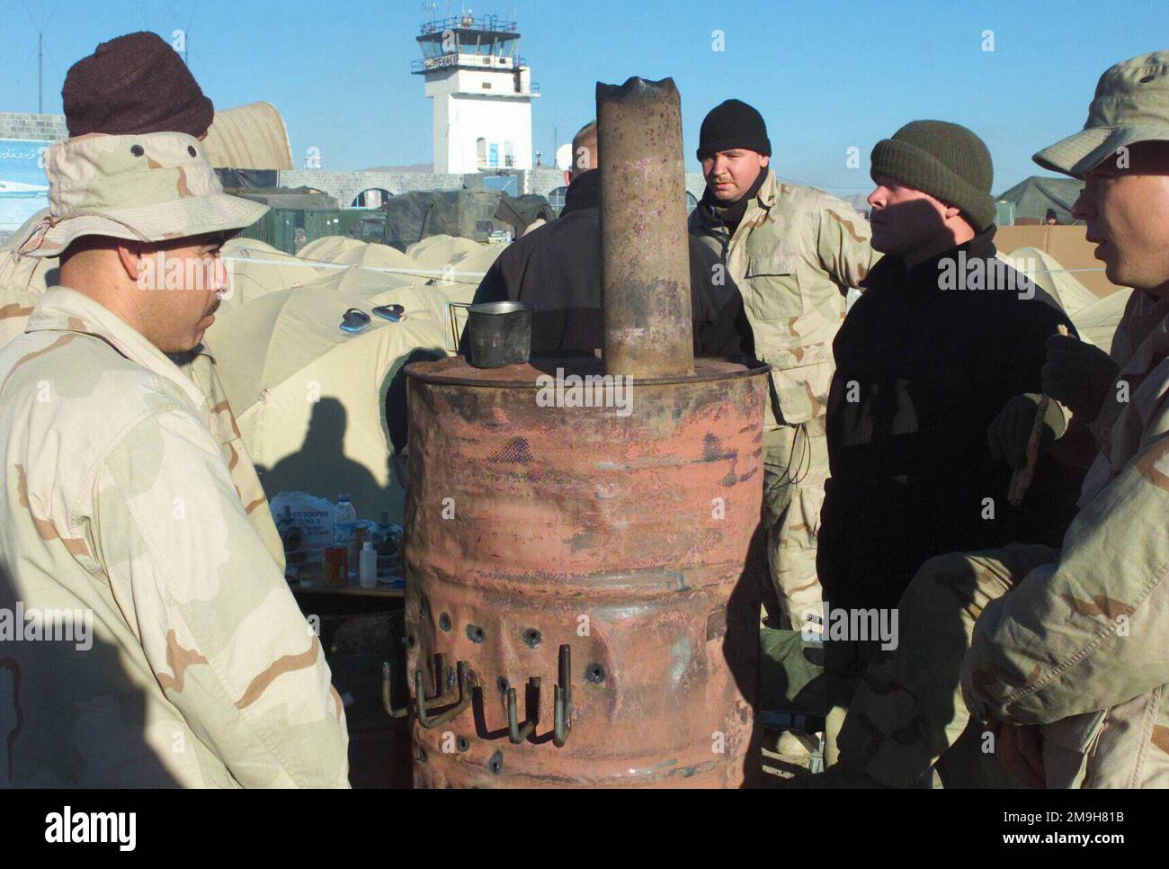 US-Marines von der Wartungseinheit, Marine Service Support Group 26, 26. Marine Expeditionary Unit (Special Operations Capable) versammeln sich um einen provisorischen Ofen, den sie mit einer 55 Gallonen fassenden Trommel und einer verbrauchten sowjetischen Artillerie-Hülle zusammenbauten. Marines sind während DER OPERATION DAUERHAFTE FREIHEIT am internationalen Flughafen Khandahar, Khandahar, Afghanistan. Betreff Operation/Serie: DAUERHAFTE FREIHEITSBASIS: Internationaler Flughafen Kandahar Land: Szene in Afghanistan (AFG) Hauptkommando gezeigt: 26. MEU (SOC) Stockfoto
