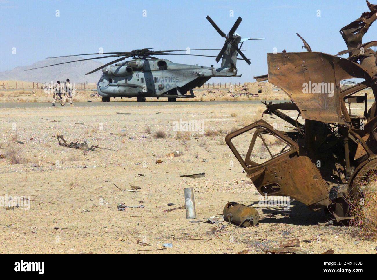 Zwei Marines gehen entlang der Landebahn in Richtung eines Marine CH-53 Sea Hallion Hubschraubers mit Marine Medium Helicopter -365 (HMM-365) (verstärkt), der sich während DER OPERATION ENDURING FREEDOM am internationalen Flughafen Khandahar, Khandahar, Afghanistan befindet. Gleich neben der Landebahn befindet sich eine große Ansammlung zerstörter sowjetischer Ausrüstung. Betreff Operation/Serie: DAUERHAFTE FREIHEITSBASIS: Internationaler Flughafen Kandahar Land: Szene in Afghanistan (AFG) Hauptkommando gezeigt: 26. MEU (SOC) Stockfoto