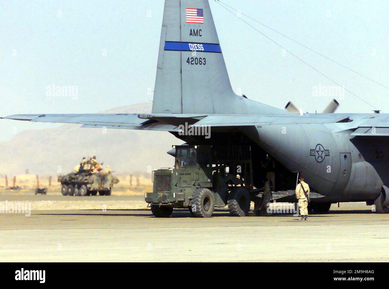 Marines der Alpha Company, 2D Light Pmored Vehicle Company, verbunden mit dem Bataillon Landing Team 3/6, 26. Marine Expeditionary Unit (Special Operations Capable), ziehen auf Patrouille in einem leichten Panzerfahrzeug (LAV-25), während ein USAF C-130, 40. Airlift Squadron, Dyess Air Force Base, Texas, Wird während DES BETRIEBS MIT einem 10K AM Lader am internationalen Flughafen Khandahar entladen. Betreff Operation/Serie: DAUERHAFTE FREIHEITSBASIS: Internationaler Flughafen Kandahar Land: Szene in Afghanistan (AFG) Hauptkommando gezeigt: 26. MEU (SOC) Stockfoto