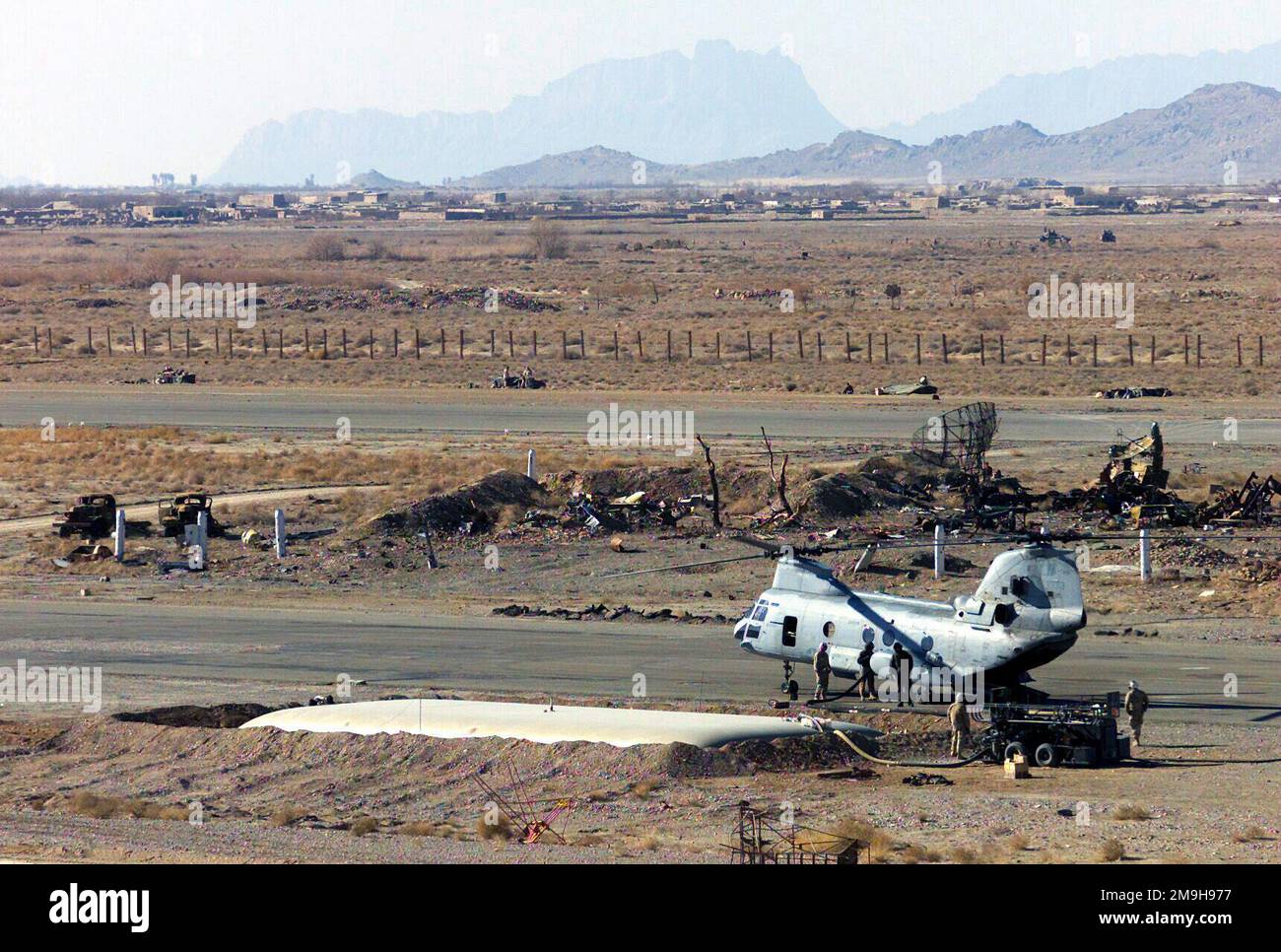 Marines mit Helicopter Marine Medium Squadron 365 (HMM-365)(verstärkt) betanken einen CH-46 Sea Knight Hubschrauber am vorderen Luftbetankungspunkt (FARP) am Air Command Element Headquarters am internationalen Flughafen Kandahar, Kandahar, Afghanistan, während DER OPERATION ENDURING FREEDOM. Die FARP enthält eine 50.000-l-Brennstoffblase, die von der US Air Force bereitgestellt wird. Dezimierte sowjetische Ausrüstung verstreut die Gegend. Marines mit Bataillonsmannschaft 3/6, 26. Marineexpeditionstruppe (Sondereinsätze möglich) sorgen für die Absperrung von den Kampfpositionen gegenüber der Landebahn. Unterg Stockfoto