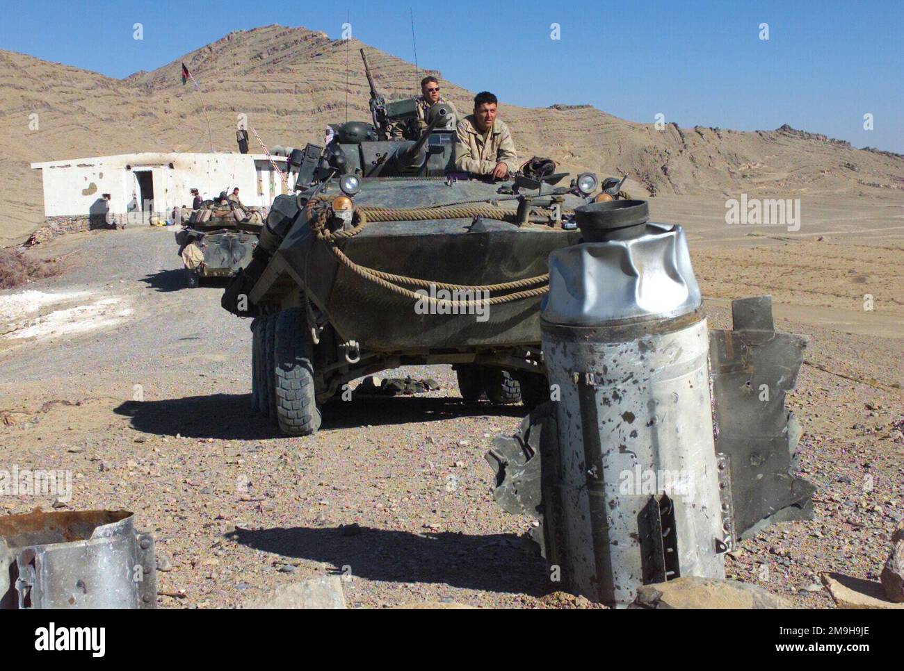 Marines mit Alpha Company, Second Light Armor Reconnaissance Battalion, 26. Marine Expeditionary Unit (Special Operations Capable) scannen das Gebiet von ihrem LAV-25 (Leichtes gepanzertes Fahrzeug) ab, während Marines für die Entsorgung von Waffen mit Explosivkraft sich darauf vorbereiten, nicht explodierte Munition in der Nähe eines Beobachtungspunkts der Anti-Taliban-Truppe in der Nähe des internationalen Flughafens Kandahar, Kandahar, Afghanistan, zu zerstören. WÄHREND DES BETRIEBS DAUERHAFTE FREIHEIT. Die ausgebrochene sowjetische Munition im Vordergrund wurde von den Afghanen verwendet, um die Gefahrenzone zu markieren. Betreff Betrieb/Serie: DAUERHAFTE FREIHEITSBASIS: Internationaler Flughafen Kandahar Land: AFG Stockfoto