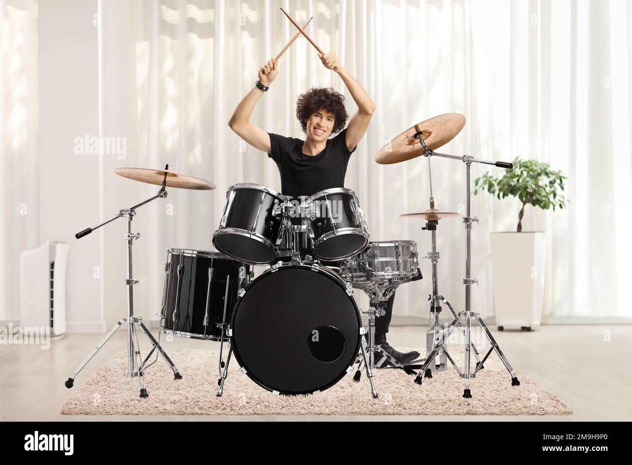 Junger männlicher Schlagzeuger, der zu Hause Schlagstöcke hält Stockfoto