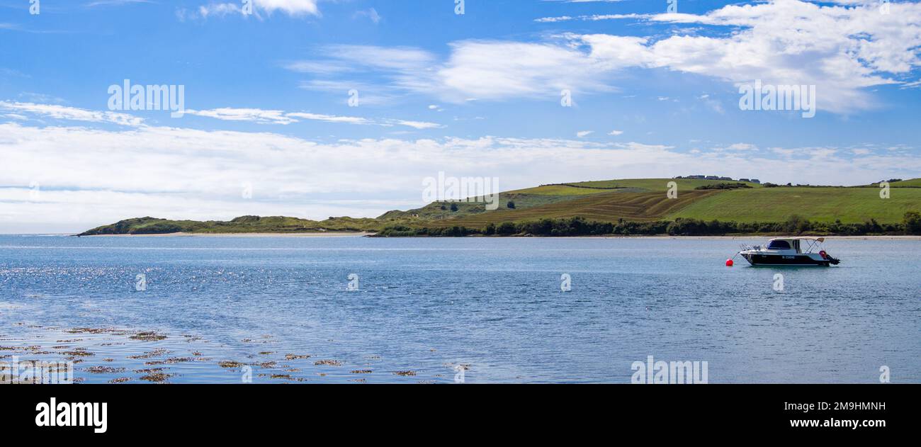 County Cork, Irland, 21. August 2022. Ein kleines Fischerboot auf einer ruhigen Wasseroberfläche in der Nähe der hügeligen irischen Küste in einem sonnigen Sommer. Boot auf dem Körper von wa Stockfoto