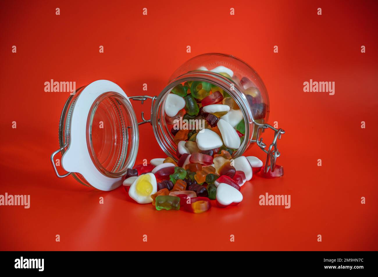 Süßigkeiten-Becher geöffnet mit Süßigkeiten auf rotem Tisch isoliert Stockfoto