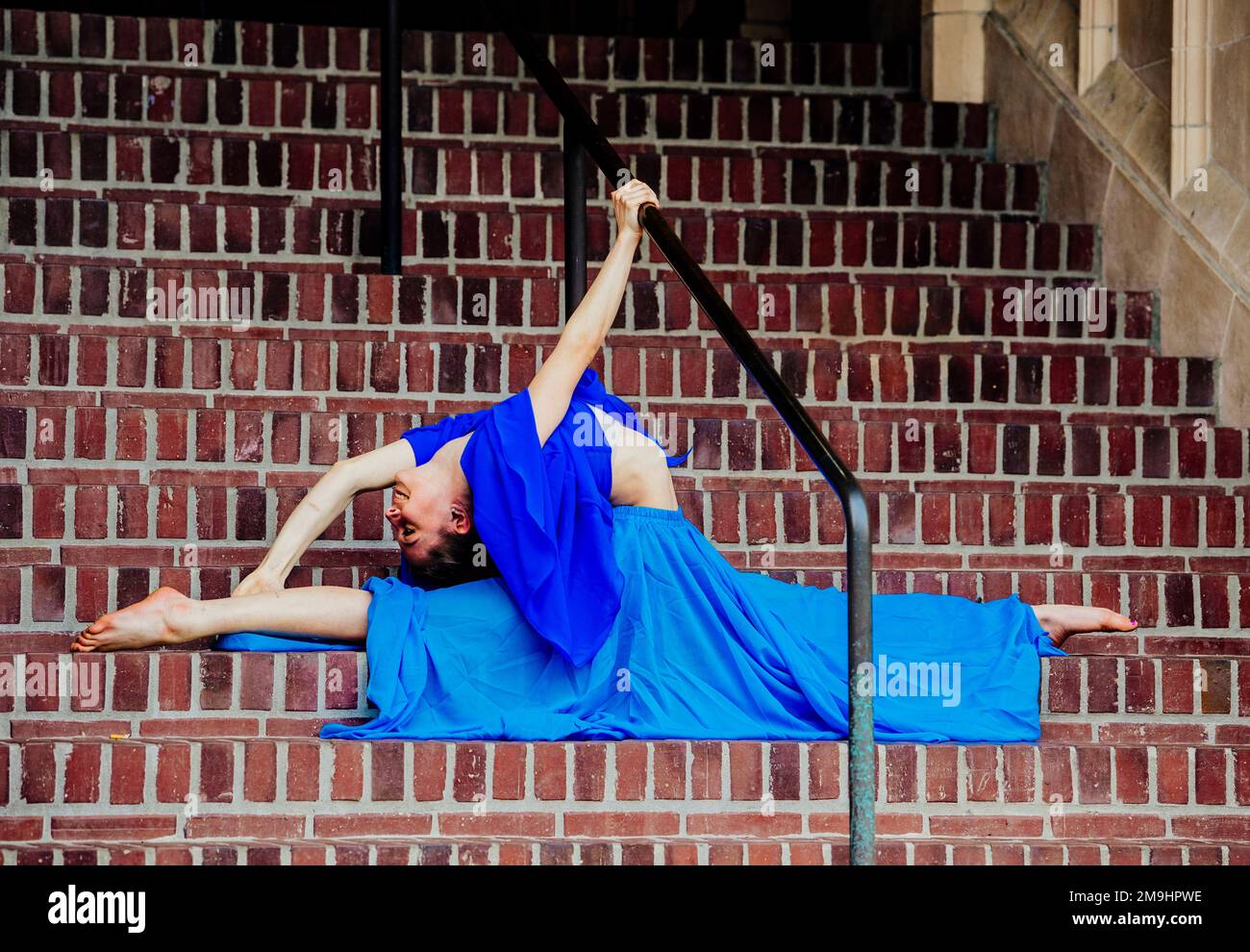 Akrobat in blauem Kleid, der sich auf der Treppe erstreckt, University of Washington, Seattle, Washington State, USA Stockfoto
