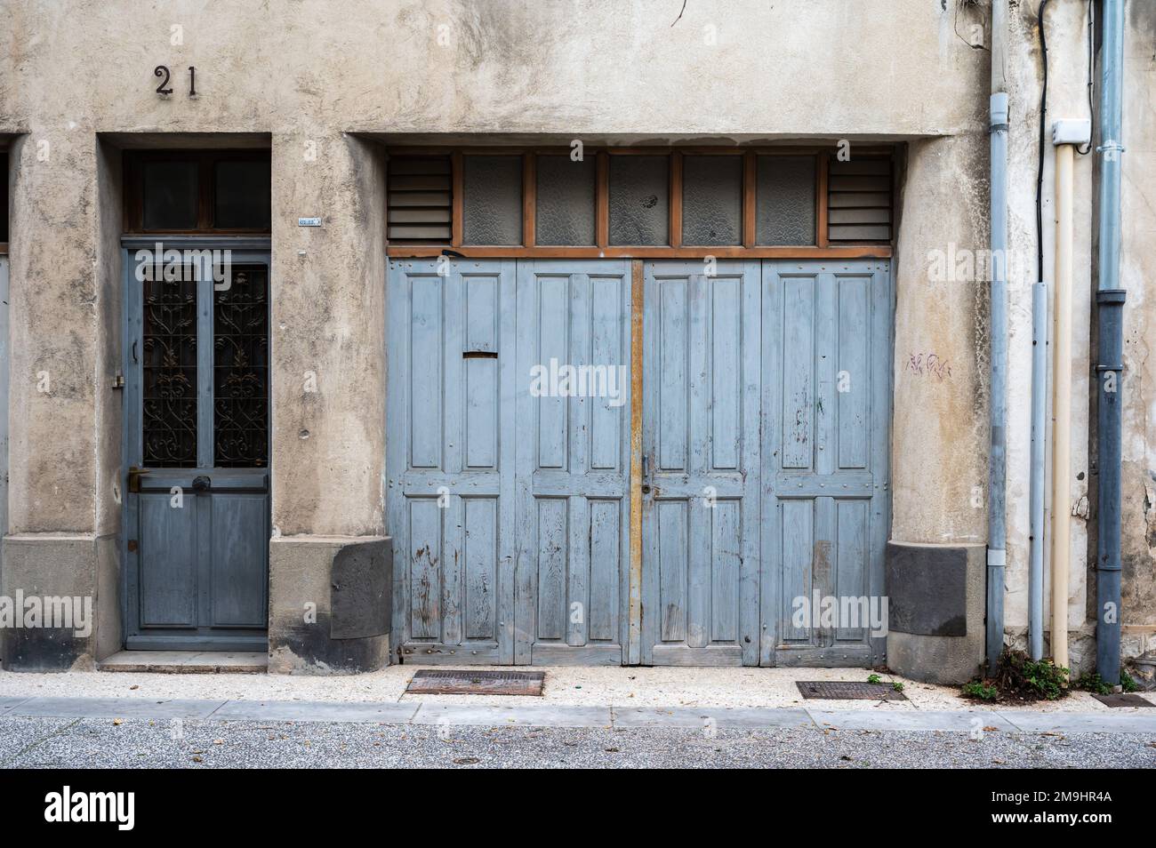 Avignon, Vaucluse, Frankreich, 12 29 2022 - abgenutzte Holzgarage und Haustür einer Wohnfassade Stockfoto