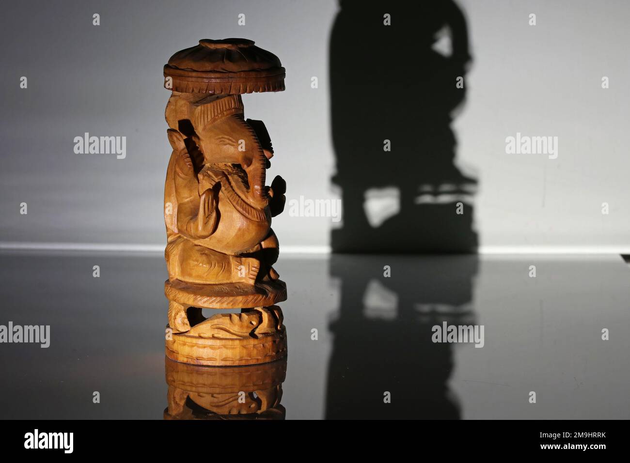 Traditionelles indisches hölzernes Souvenir. Gott, Ganesha. Foto im Dunkeln im Strahl einer Laterne. Stockfoto