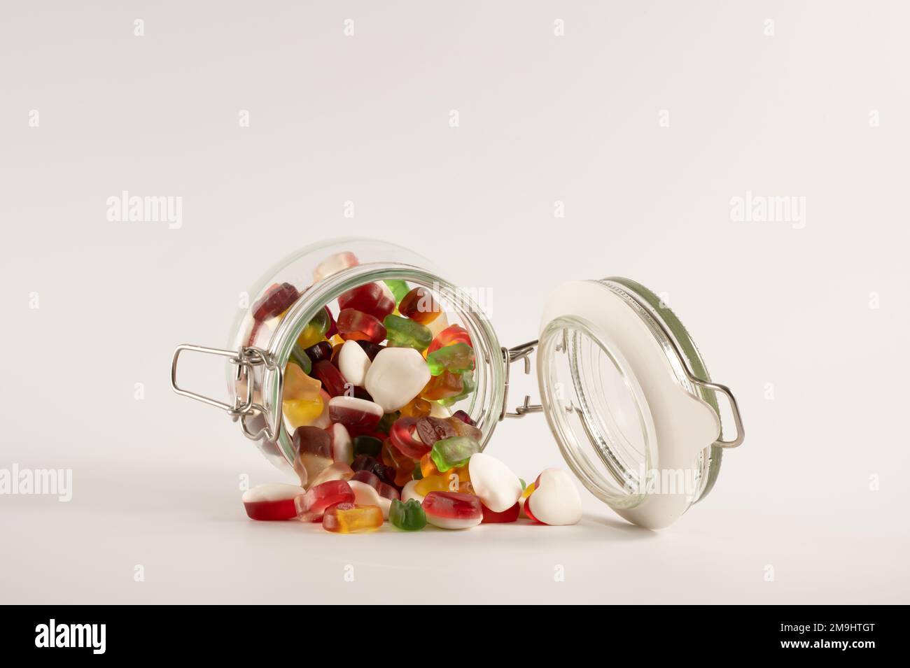 Glas-Süßigkeitenglas auf einem weißen Tisch mit Süßigkeiten mit Fruchtgeschmack isoliert auf weißem Hintergrund Stockfoto